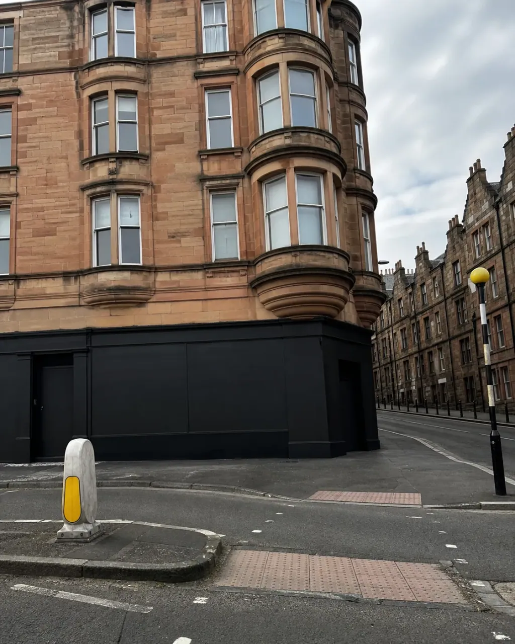 A curved red sandstone tenement block turning a Tollcross corner