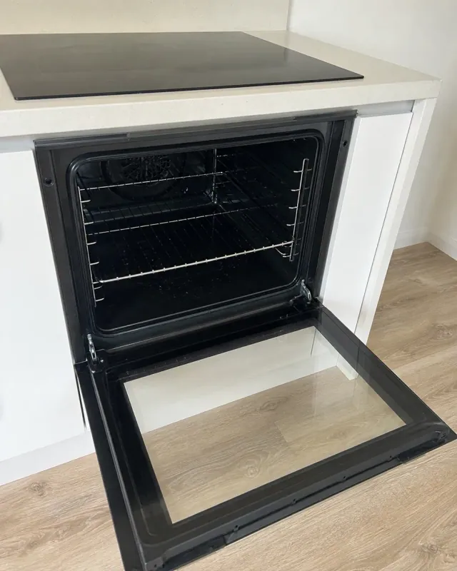 A clean empty oven with the door open and both racks back in place